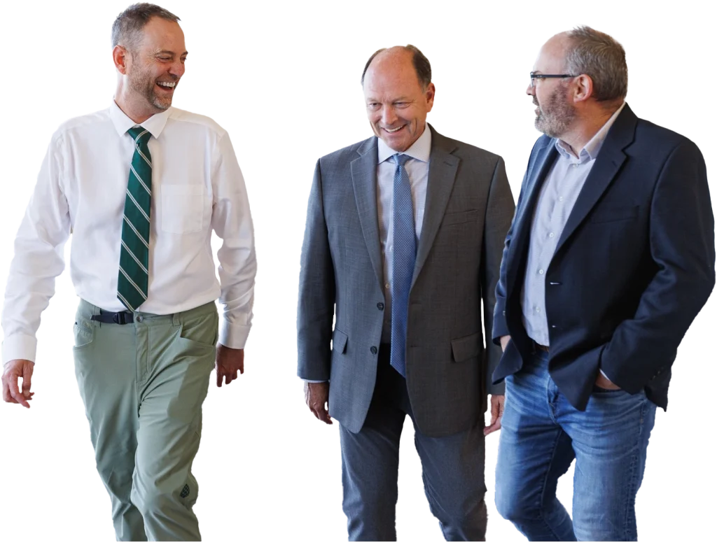 Three men in business attire are walking together and conversing about Independent Cost Estimating.